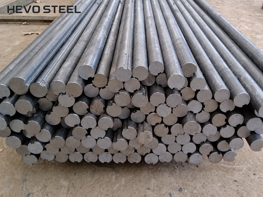 Long solid grooved shaft stock stacked with cut ends visible.