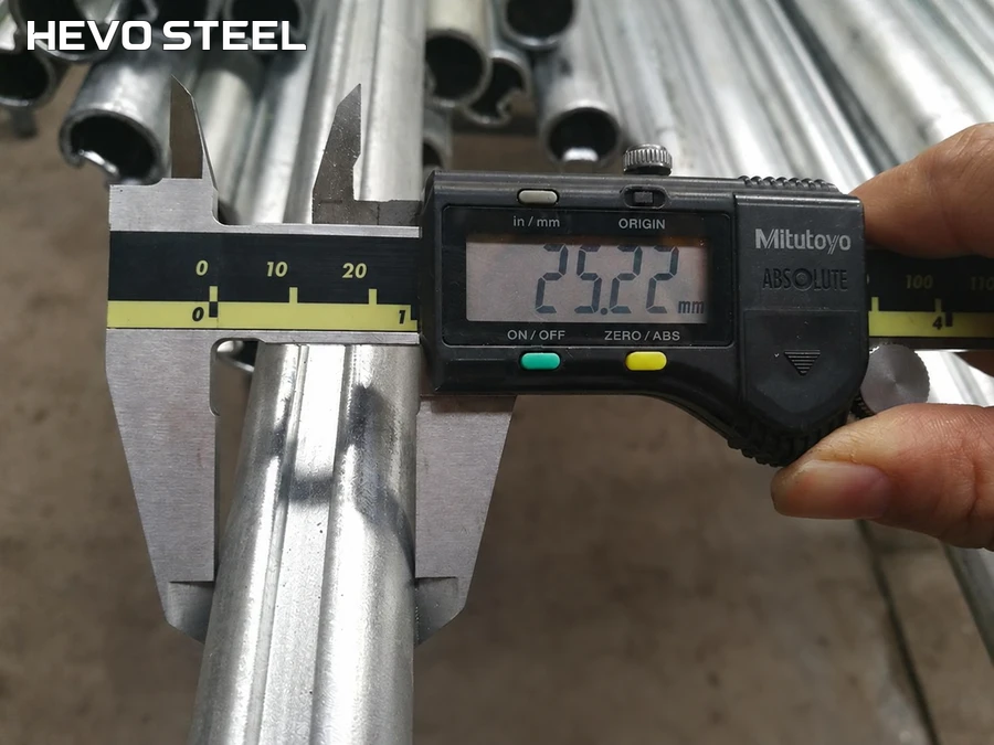 Digital caliper positioned across the outside of a grooved hollow tube.